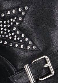 Bota de cuero negra con un diseño de estrella adornado con tachuelas plateadas y rhinestones. Incluye un hebilla metálica brillante en una correa.
