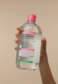 Clear, round plastic bottle with a pink cap, containing 700 ml of Garnier SkinActive Micellar Cleansing Water. Labels in German. Recyclable material.