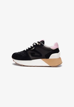 Scarpa da ginnastica nera con lacci bianchi, linguetta rosa sul tallone, punta con trama e suola spessa bianca e beige su sfondo bianco.
