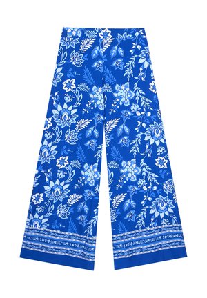 Pantalon à jambes larges avec motifs floraux bleus et blancs et bandes décoratives le long de l'ourlet sur un fond blanc uni.