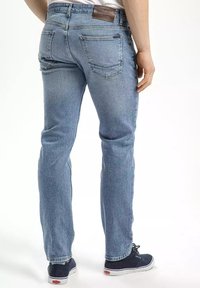 Jasnoniebieskie dżinsy o prostym kroju, z skórzaną naszywką na plecach, dwiema tylnymi kieszeniami i delikatnym wyblaskiem.