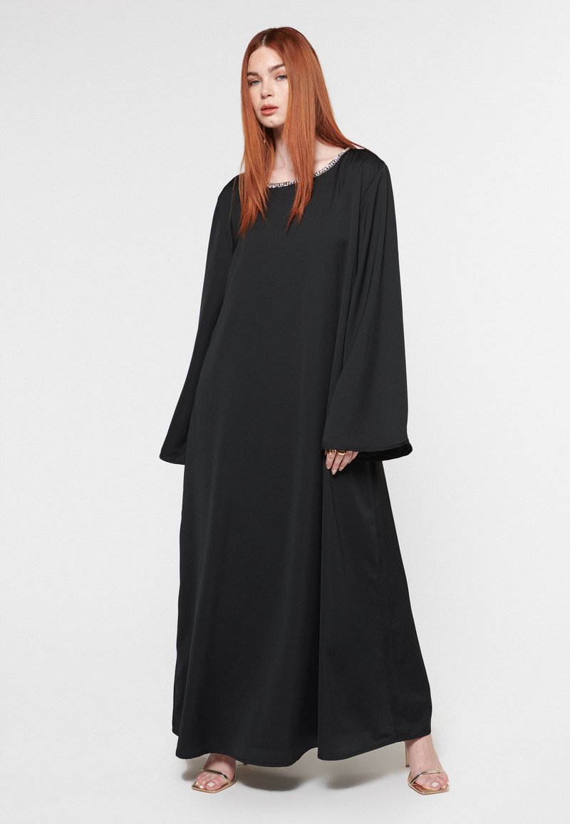 Vestido negro de manga larga con escote cuadrado y detalle plateado en el cuello, hecho de una tela suave, que fluye hasta el suelo.