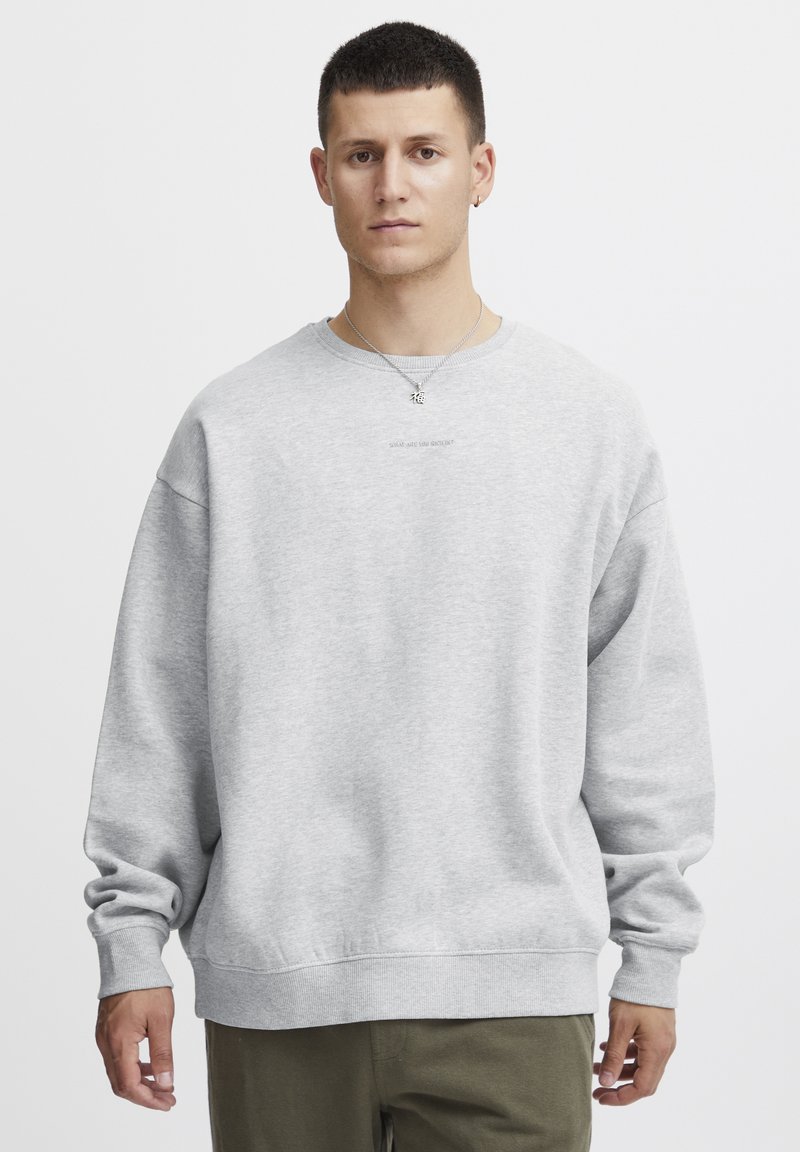 Grijze sweatshirt met een ronde hals, oversized pasvorm en geribde manchetten. Minimalistische tekstdetails op de borst. Zacht, gestructureerd materiaal.