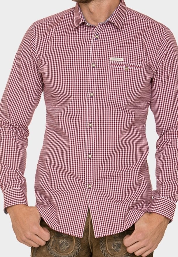 Homme portant une chemise à manches longues à carreaux rouges et blancs avec des boutons et un pantalon traditionnel brodé marron.