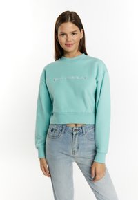 Turquoise cropped sweatshirt met lange mouwen, geribbelde manchetten en een ronde hals. Beschikt over geborduurde tekst in contrasterende kleuren over de voorkant.