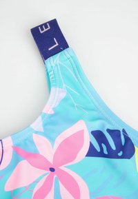 Wielokolorowy top kąpielowy z kwiatowym wzorem w różu i niebieskim, wykonany z elastycznego materiału, z niebieskim paskiem z logo dla lepszego wsparcia.