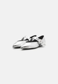 Ballerines métalliques argentées à bout pointu, dotées de brides croisées et d'une boucle cloutée. Texture lisse et design profil bas.