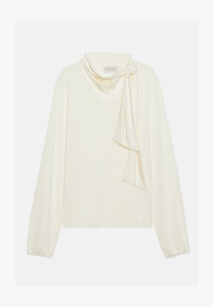 Kermanvärinen pitkähihaine paita V-pääntie ja solmittu huivitieto kauluksessa. Sujuva pinta, jossa on laskostetut hihat.