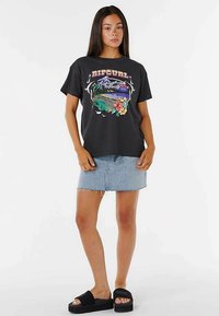 Black t-shirt with colorful floral and landscape graphic, paired with a denim mini skirt and black slide sandals. Casual outfit.