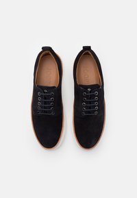 Scarpe lacci in suede blu navy con accento in pelle marrone, punta rotonda e suola in gomma color crema. Presentano sei occhielli e logo all'interno.