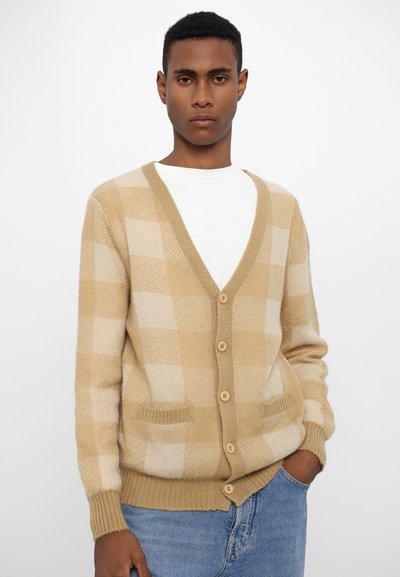 Beige och creamrutig cardigan med V-hals, knappstängning och fickor, tillverkad av ett mjukt, texturerat stickat tyg.