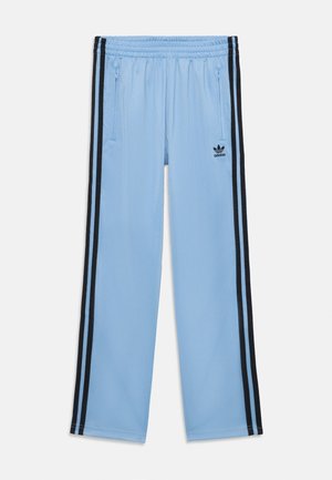 Lichtblauwe Adidas trainingsbroek met elastische tailleband, zwarte strepen aan de zijkanten, ritszakken en Adidas-logo op de linker dij.