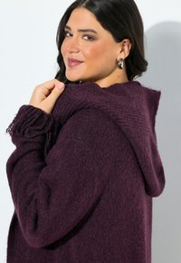 Lila Kapuzenjacke aus weichem, strukturiertem Stoff. Mit gerippten Details an den Bündchen und einer lockeren Passform. Keine sichtbaren Verschlüsse.