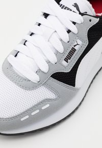 Grey and white sneaker with mesh and suede textures, featuring white laces, a black accent, and a branded tag with the Puma logo.