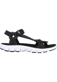 Black fabric sandals with a textured strap design, white sole, and black rubber tread. Features an adjustable strap for a secure fit.