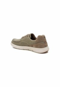 Zapatillas con cordones, de parte superior de tela en verde olivo y detalles de ante. Suela blanca gruesa con ranuras de flexibilidad. La parte trasera presenta el logo.