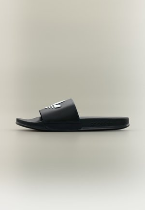 Sandale slide en caoutchouc noir avec une large bride comportant un logo Adidas Trefoil blanc sur un fond neutre.