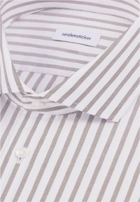 Chemise blanche avec de fines rayures verticales marron et une étiquette visible sur le col portant la mention seidensticker.