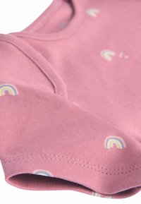 Chemise en coton rose à manches courtes, avec de petits motifs arc-en-ciel. Texture lisse avec un col arrondi et des détails de couture sur l'ourlet.