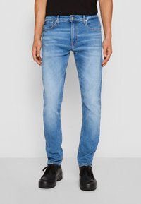 Vaaleansiniset farkut, slim fit -leikkaus, viiden taskun malli ja hillitty haalistuma. Yhdistetty mustiin nauhakenkään.