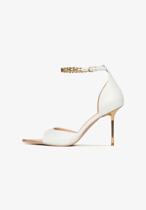 Hvide læder højhælede sandaler med åben tå, ankelrem med guldfarvede detaljer og en slank stiletto hæl.