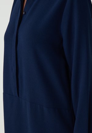 Navy blauwe, langemouwen shirt met een knoopsluiting, gladde stof en een ontspannen pasvorm met een naaddetail op de taille.