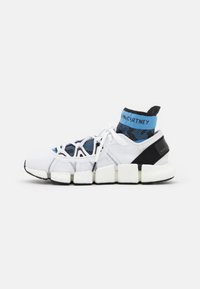 Baskets blanches de sport avec un dessus en maille texturée, un col imitant des chaussettes bleu et noir, une semelle blanche épaisse et des accents noirs au niveau du talon.