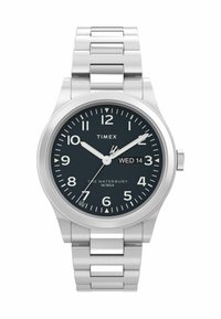 Montre en acier inoxydable avec un bracelet argenté, cadran noir, index horaires blancs et affichage de la date. Dispose de aiguilles lumineuses et d'une conception étanche.