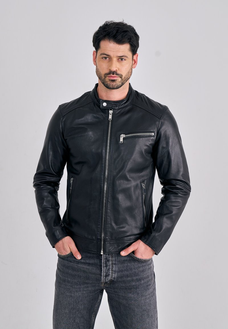 Černá kožená bunda s límcem, s předním zapínáním na zip a zipovými kapsami na hrudi a boku. Hladká textura, přiléhavý střih.