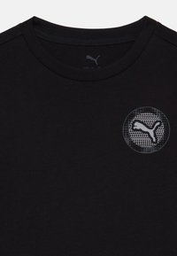 Camiseta de algodón negra con un logo redondo gris con un patrón de red, cuello redondo y mangas cortas. Textura suave en toda la prenda.