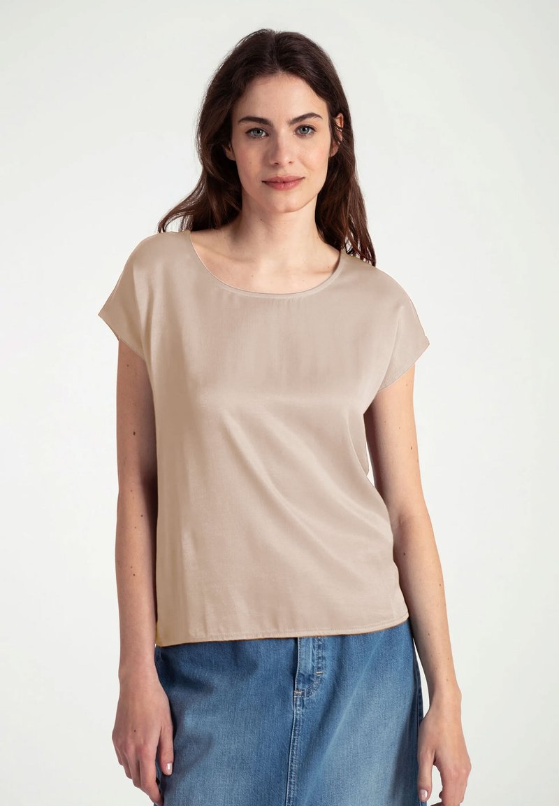 Beige top met korte mouwen en ronde halslijn, zachte textuur en een losse pasvorm, gecombineerd met een denim rok.