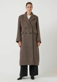Abrigo largo mezcla de lana marrón, cruzado con dos botones grandes, solapas con muesca, bolsillos laterales y un acabado texturizado. Mangas largas.