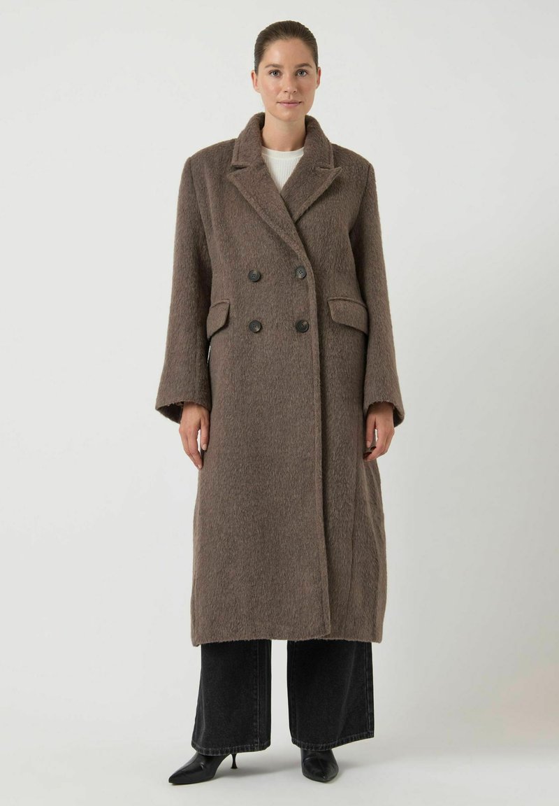 Abrigo largo mezcla de lana marrón, cruzado con dos botones grandes, solapas con muesca, bolsillos laterales y un acabado texturizado. Mangas largas.