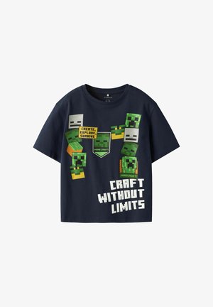 Tums zilā krāsa ar īsām piedurknēm izgatavota no kokvilnas, ar Minecraft tēmas grafiku, kurā iekļauti pikselēti tēli un teksts.