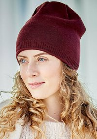 Maroon knitted beanie hat with a soft texture and elongated shape, featuring a rolled rim and subtle stitching details.