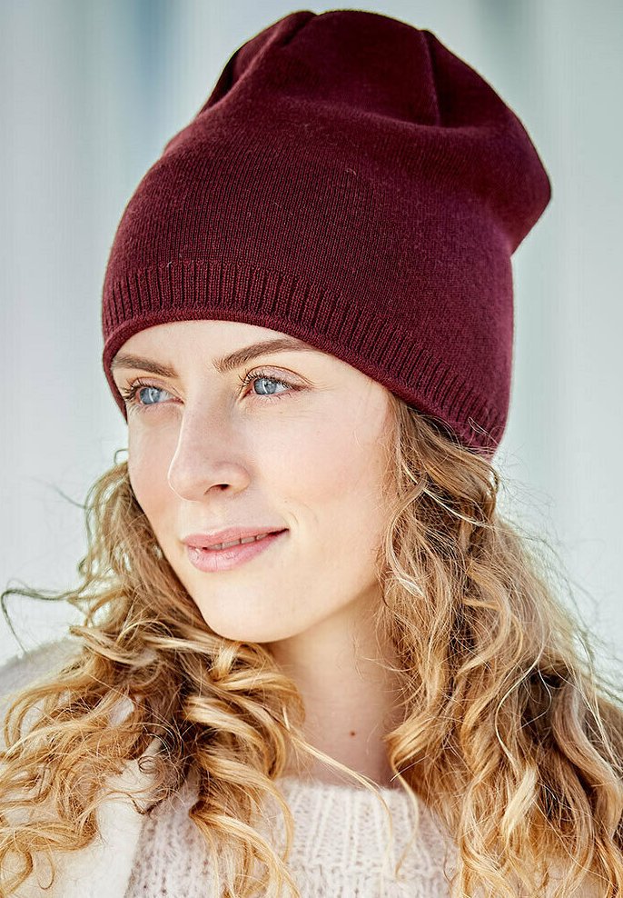Maroon knitted beanie hat with a soft texture and elongated shape, featuring a rolled rim and subtle stitching details.