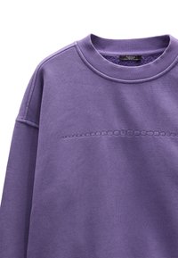 Fioletowa bluza wykonana z bawełnianej mieszanki, z prążkowanym dekoltem, teksturowanym poziomym wzorem oraz wszytymi rękawami.