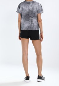 Gray and black patterned short-sleeve top paired with black shorts. Black shoes complete the athletic outfit. The fabric has a smooth texture.