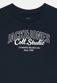 Námornícky modré bavlnené tričko s okrúhlym výstrihom a bielym potlačeným textom: "JACK & JONES Coll. Studio Created by the J&J crew Since 1990."