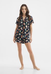 Nawet zestaw piżamowy z krótkim rękawem w kolorze granatowym, z zabawnym nadrukiem kotów i przedmiotów takich jak prezenty. Wykonany z miękkiego materiału, o luźnym kroju.