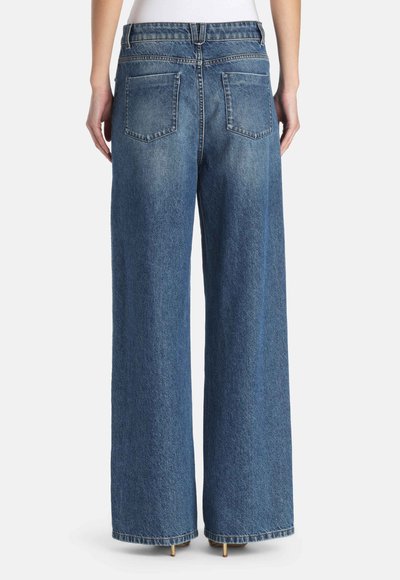 Traperice širokih nogavica plave boje s izblijedjelim pranjem. Imaju dva stražnja džepa i prošivene detalje duž struka i rubova.