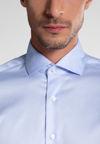 Camicia da uomo in cotone azzurro chiaro con colletto strutturato, stile mandarina, con bottoni bianchi e texture liscia.