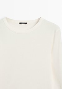 Cream-colored long-sleeve t-shirt, made of soft cotton, featuring a round neckline and minimal stitching details.