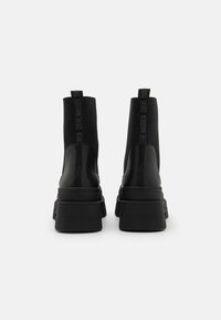 Stivali neri alla caviglia con un design elegante, presentano una tomaia in pelle liscia e lati elastici. Suola spessa con il marchio "STEVE MADDEN" sul tallone.