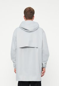 Helehall pullover jakk, millel on kapuuts, kihiline tagakujundus, pikad varrukad ja lõdvestunud istuvus. Sile ja kerge kangastekstuuri.