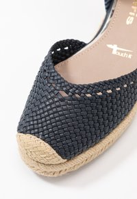 Tmavě modrá tkaná espadrilka s kulatou špičkou, zdobená jutovými prvky na podrážce a otevřeným designem pro lepší prodyšnost.