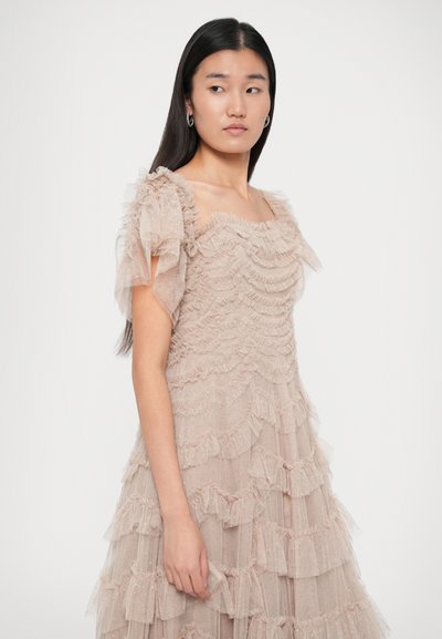 Kübe roosa kihiline kleit, mis on valmistatud pehmest, läbipaistvast kangast koos ruffle detailidega ja lühikeste, puffse varrukatega. Ruudu kujuline dekoltee ja voogav siluett.