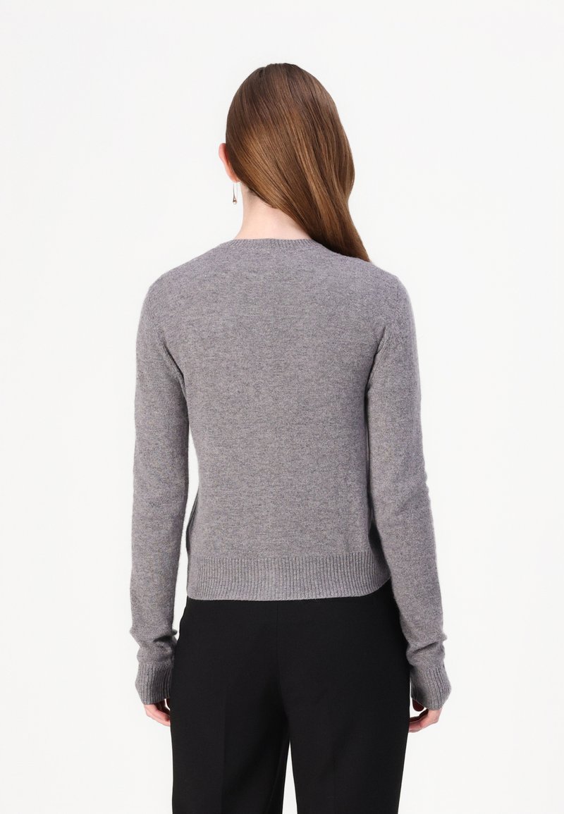 Grauer Strickpullover mit langen Ärmeln, rundem Ausschnitt und geripptem Saum. Das Material wirkt weich mit einer glatten Textur. Keine sichtbaren Muster.