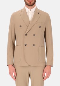 Beige dubbelzijdig jasje gemaakt van gladde stof met twee voorkanten zakken en donkere knoopaccenten. Inclusief een notch lapel en een getailleerde pasvorm.