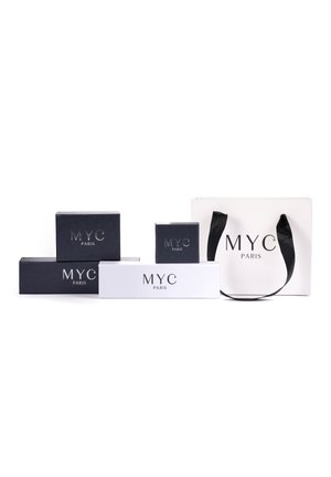 Collection d'emballages MYC Paris, comprenant des boîtes noire et blanche avec des logos en relief et un sac en papier blanc avec des poignées noires.